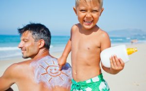 A little boy applying sunscreen in Adelaide beach to protect against skin cancer